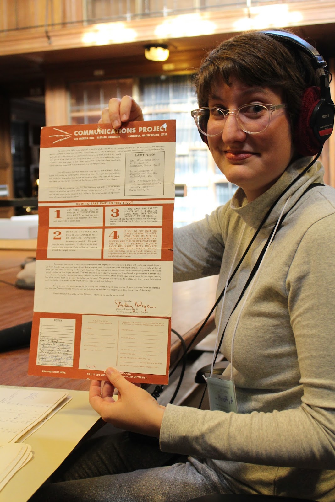 Producer Annie Minoff, with headphones on, holds up an old letter experiment.