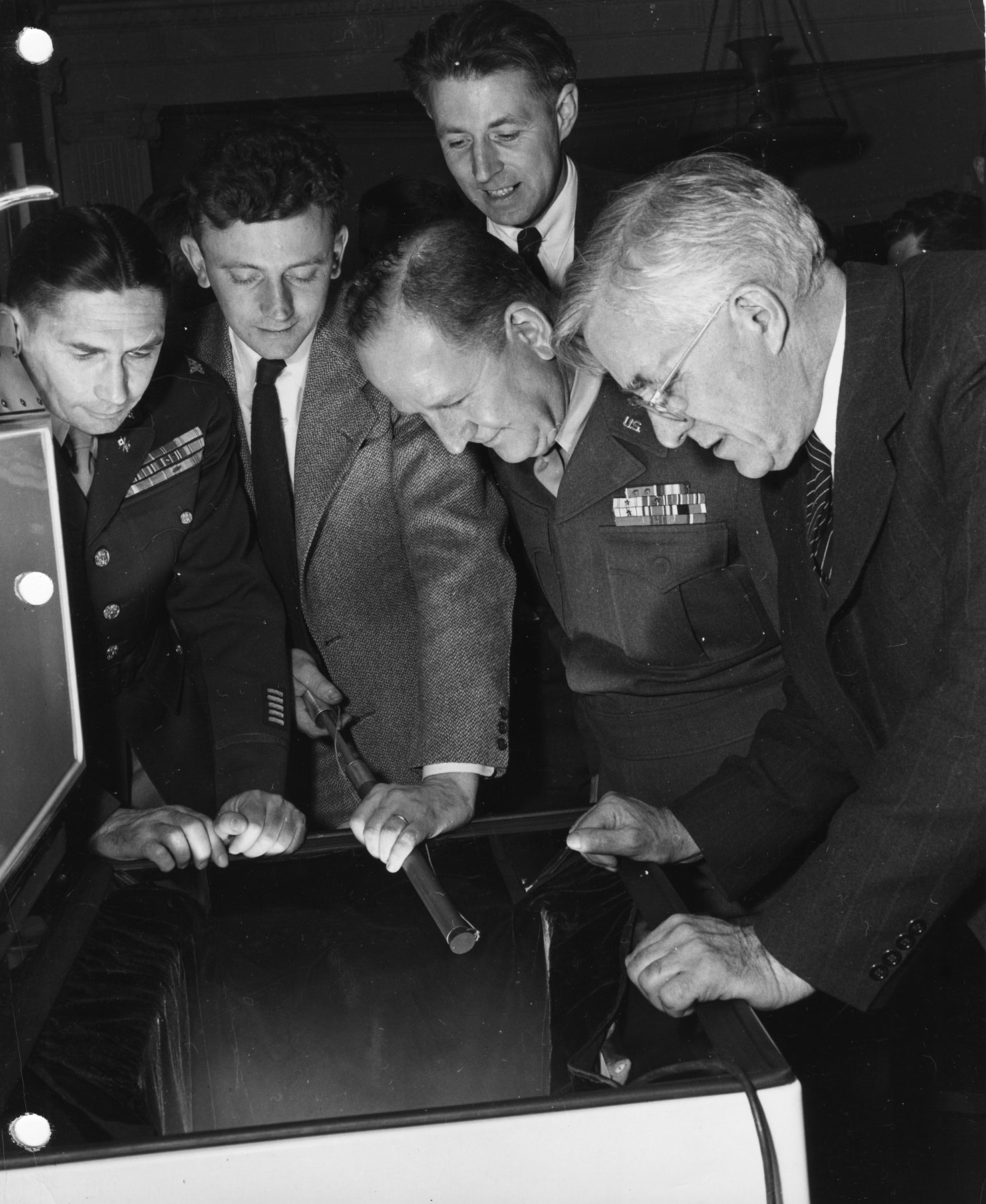 Vincent Schaefer and four other men in military uniforms peer into the container.