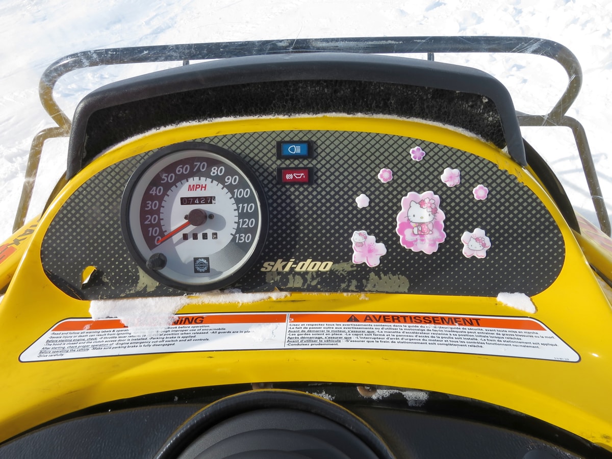 the dashboard of a snowmobile that has hello kitty stickers next to the speedometer.