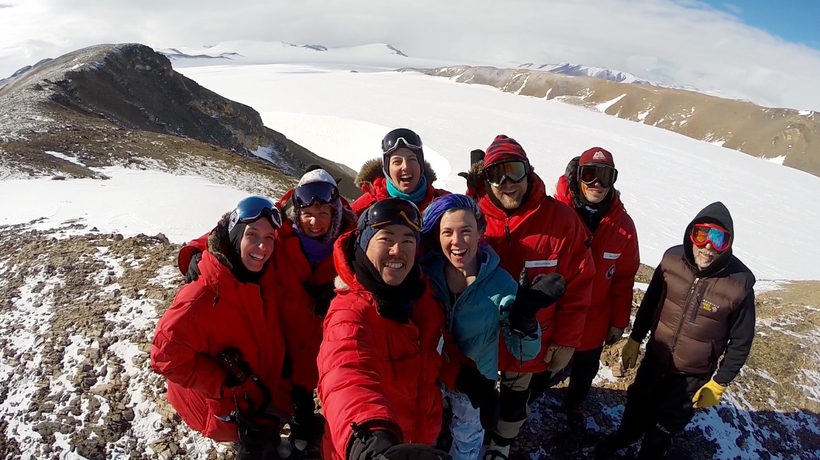 The group of scientists pose in front of the landscape.